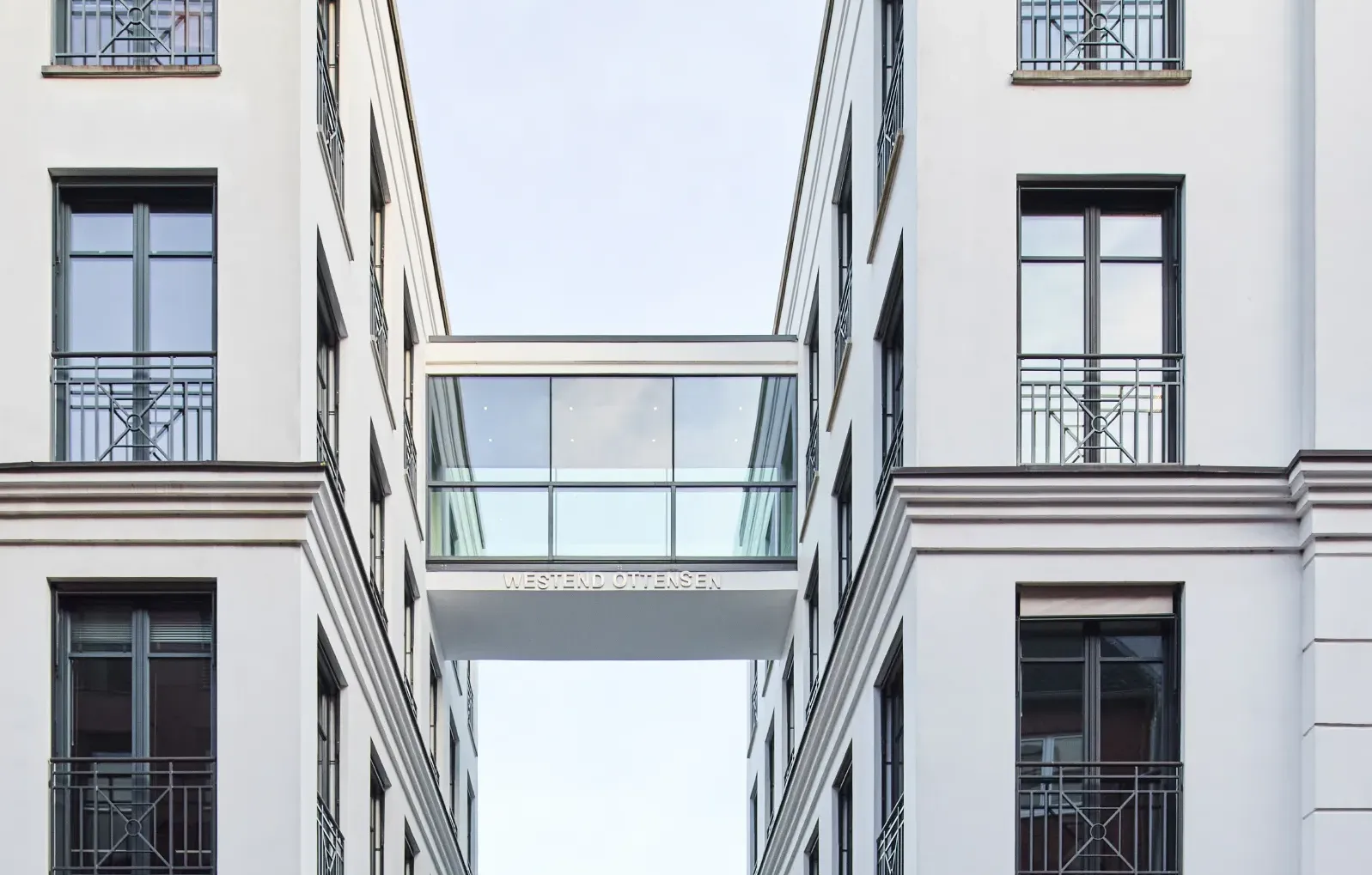 Moderne Bürogebäude mit Glasbrücke verbinden zwei weiße Fassaden in Ottensen, umgeben von einer ruhigen Straße.
