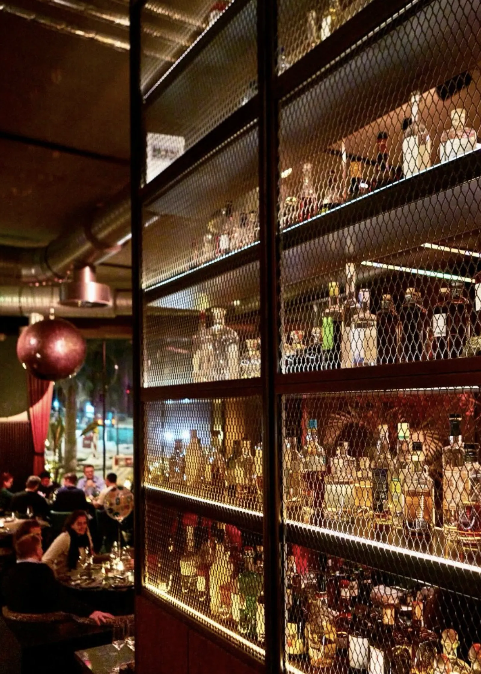 Eine stilvolle Bar mit glänzenden Spirituosenflaschen, die das moderne Soulfood-Erlebnis im DER PLAYER in Ottensen unterstreichen.